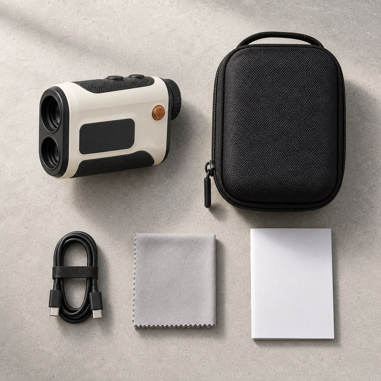 Telémetro, estuche, cable USB-C, paño y manual dispuestos sobre una mesa